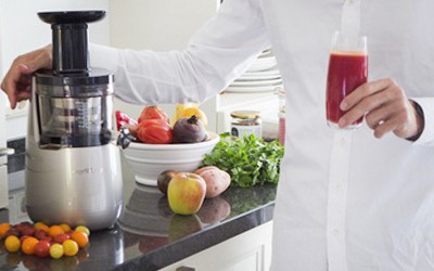 Licuadora lento en la cocina con muchos zumos de frutas y verduras